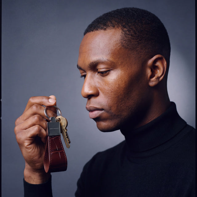 Man holding up a burgundy crocodile-embossed leather keychain by GENTCREATE with house keys