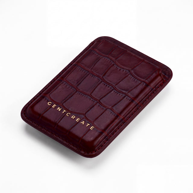 Burgundy crocodile-embossed leather magnetic card wallet by GENTCREATE lying at an angle on white