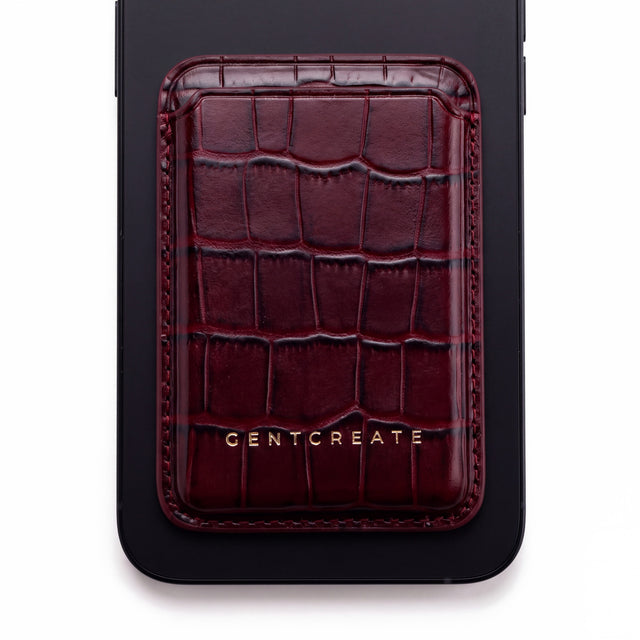 Burgundy crocodile-embossed leather magnetic card wallet by GENTCREATE on the back of a phone, on white
