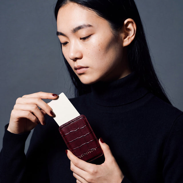 Woman taking a card out of a burgundy crocodile-embossed leather magnetic card wallet by GENTCREATE