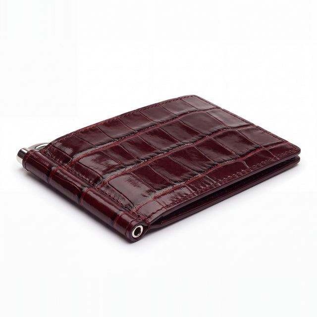 Closed burgundy glossy crocodile-embossed leather money clip wallet by GENTCREATE with its silver clip, on white