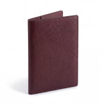 Closed burgundy lizard-embossed leather passport holder by GENTCREATE standing on white
