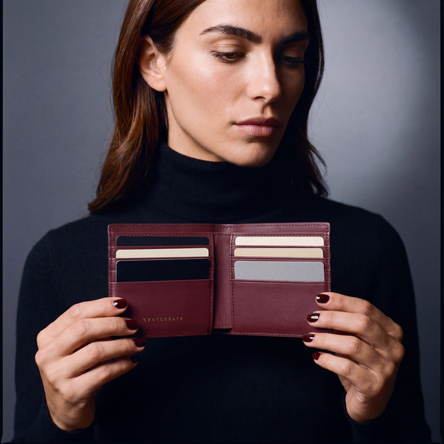 Woman opening a burgundy lizard leather bifold wallet by GENTCREATE to show the card slots