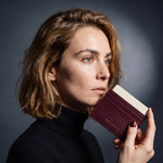 Woman holding a slim burgundy lizard-embossed leather card holder by GENTCREATE and drawing out a card