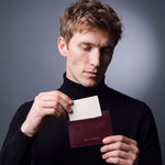 Man sliding a card into a burgundy lizard-embossed leather card holder by GENTCREATE