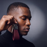 Man holding a burgundy lizard-embossed leather keychain by GENTCREATE up beside the face