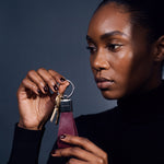 Woman holding up a burgundy lizard-embossed leather keychain by GENTCREATE with house keys