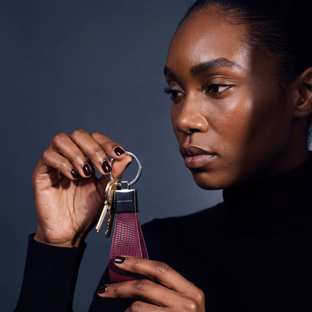 Woman holding up a burgundy lizard leather keychain by GENTCREATE with house keys