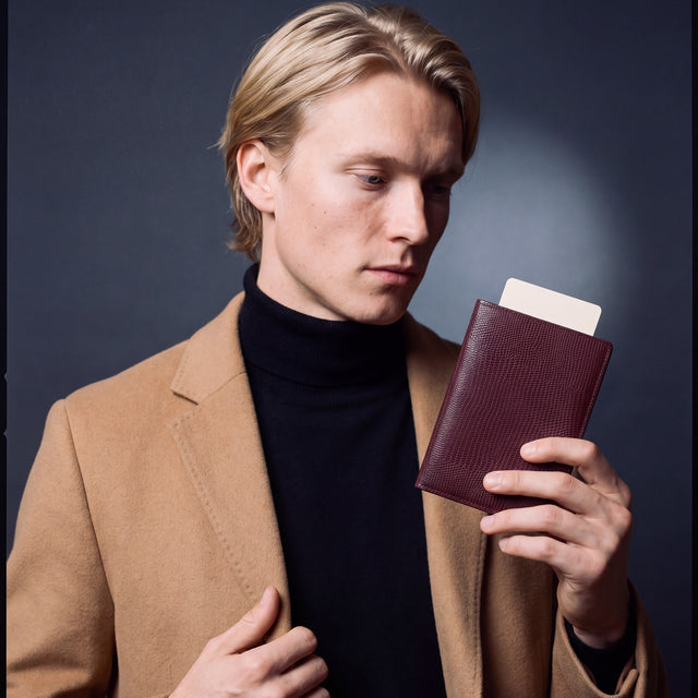 Man holding a burgundy lizard leather passport holder by GENTCREATE with a blank card tucked in
