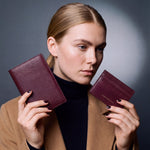 Woman holding a matching burgundy lizard-embossed leather passport holder and card holder set by GENTCREATE