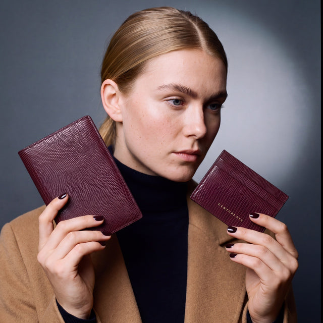 Woman holding a matching burgundy lizard leather passport holder and card holder set by GENTCREATE