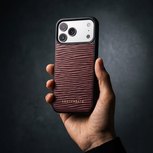 Hand holding a burgundy wave-embossed leather iPhone 18 Pro Max case by GENTCREATE in a single studio light