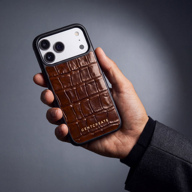 Man's right hand holding a brown crocodile-embossed iPhone 18 Pro case by GENTCREATE, seen from his point of view
