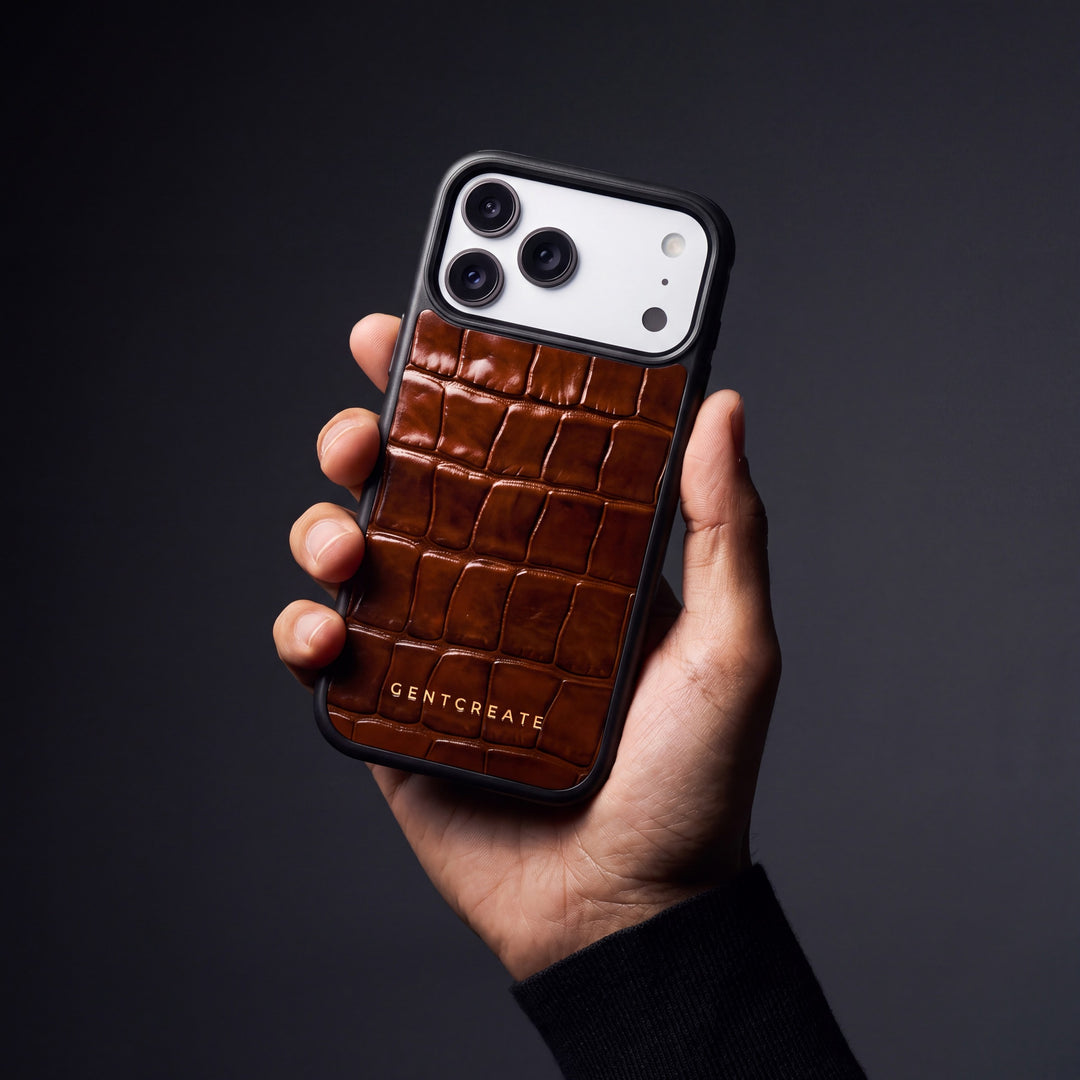 A hand holds an iPhone in a brown crocodile-embossed GENTCREATE case cut for its model