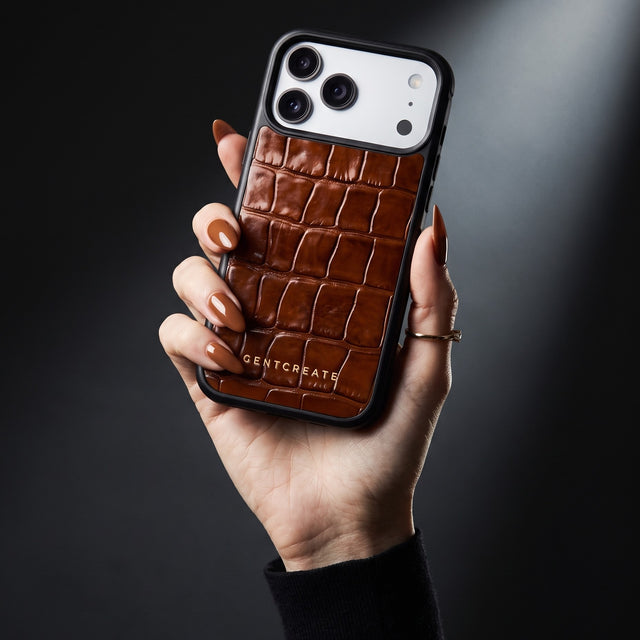 Hand with cognac nails holding a brown glossy crocodile-embossed calfskin iPhone 18 Pro Max case by GENTCREATE