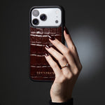 Hand with oxblood nails holding a burgundy glossy crocodile-embossed calfskin iPhone 18 Pro Max case by GENTCREATE