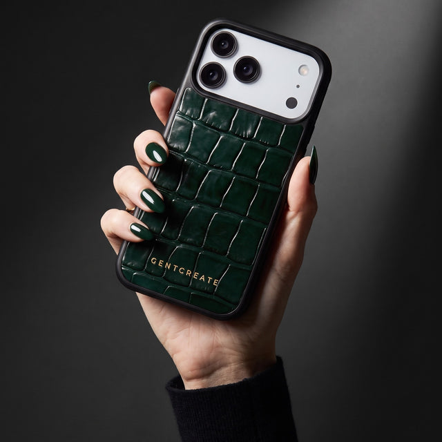 Hand with forest-green nails holding a green glossy crocodile-embossed calfskin iPhone 18 Pro Max case by GENTCREATE