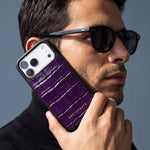 Homme à lunettes de soleil tenant contre sa joue une coque iPhone 18 Pro Max GENTCREATE en veau magenta brillant embossé façon crocodile