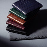 Crocodile-embossed leather bifold wallet by GENTCREATE in black, burgundy, brown, green and navy, stacked