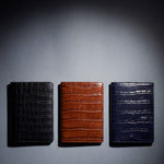Crocodile-embossed leather passport holder by GENTCREATE in black, brown and navy, laid flat