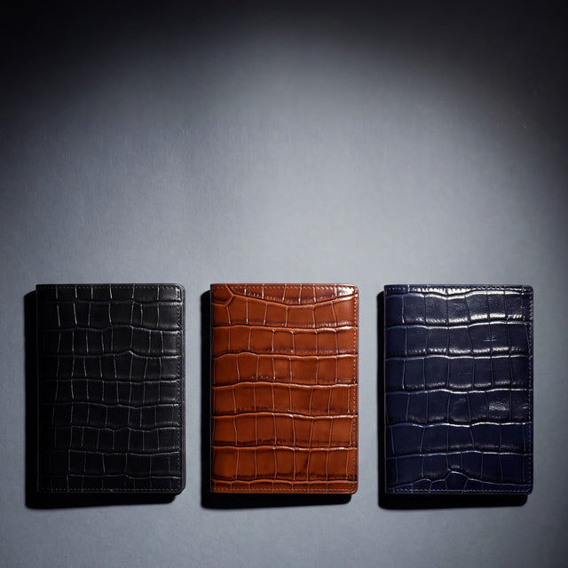 Crocodile-embossed leather passport holder by GENTCREATE in black, brown and navy, laid flat