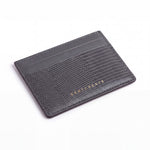 Gray lizard-embossed leather business card holder by GENTCREATE lying at an angle on white
