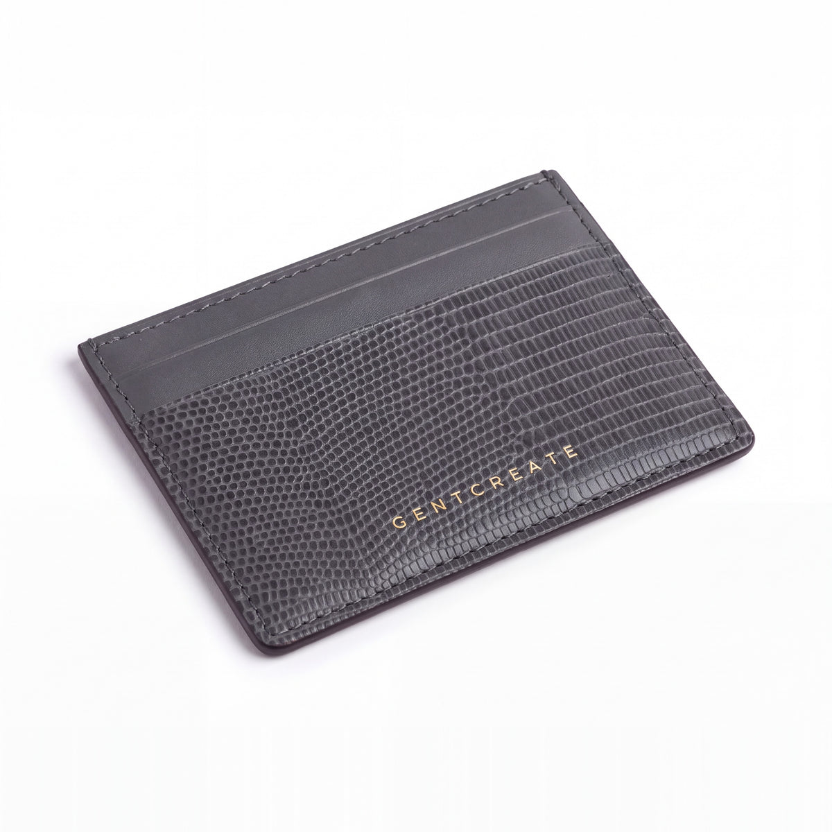 Gray lizard-embossed leather business card holder by GENTCREATE lying at an angle on white