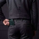 Man sliding a green crocodile-embossed leather bifold wallet by GENTCREATE into his back trouser pocket