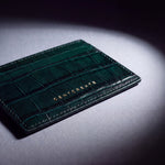 Close-up of the gold GENTCREATE stamp on a green crocodile-embossed leather card holder