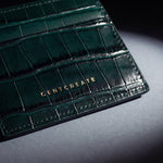 Close-up of the gold GENTCREATE stamp pressed into a green crocodile-embossed leather card holder