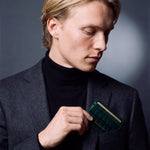 Man slipping a green crocodile-embossed leather card holder by GENTCREATE into a blazer chest pocket