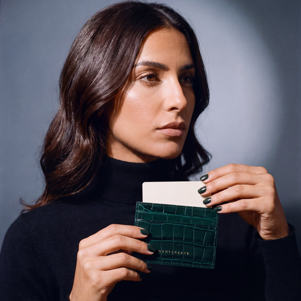 Woman sliding a card into a green crocodile-embossed leather card holder by GENTCREATE