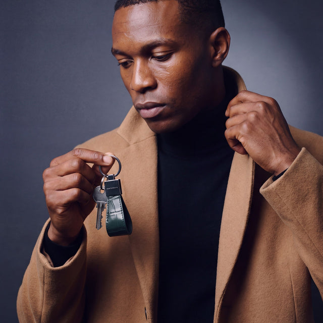 Man holding a green crocodile-embossed leather keychain by GENTCREATE with house keys