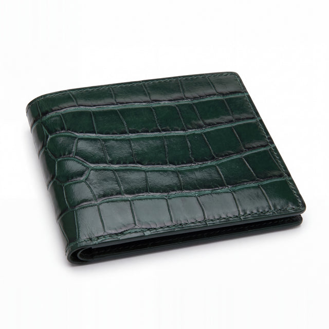 Closed green glossy crocodile-embossed leather bifold wallet by GENTCREATE lying on white
