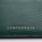 Close-up of the gold GENTCREATE stamp on a green lizard-embossed leather card holder