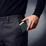 Man sliding a green pebble leather card holder by GENTCREATE into his trouser front pocket
