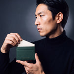 Man sliding a card into a green pebble leather card holder by GENTCREATE