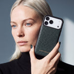 Kvinde holder et grønt iPhone 18 Pro Max-cover i narvet kalveskind fra GENTCREATE ved siden af ansigtet i dagslys fra et vindue