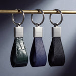 Keychains by GENTCREATE in crocodile-embossed, lizard-embossed and Saffiano leather, on a brass rail