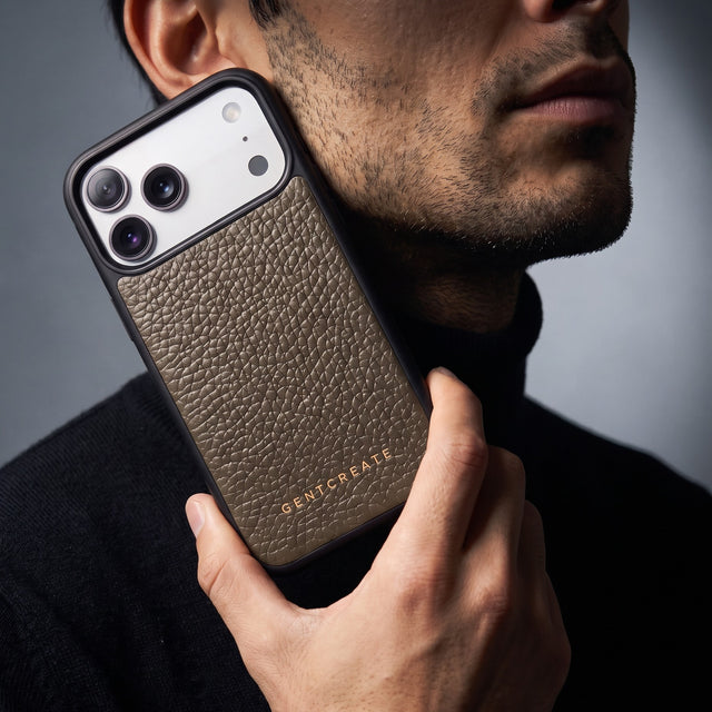 Man holding a khaki pebble-grain leather iPhone 18 Pro Max case by GENTCREATE against his jaw