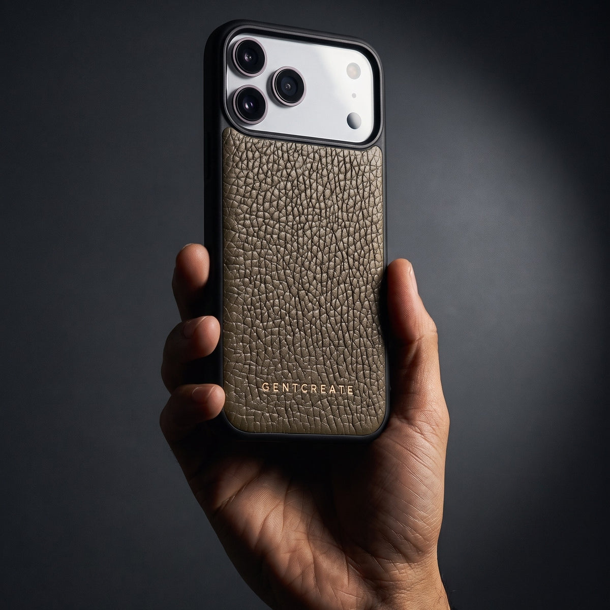 Hand holding a khaki pebble-grain leather iPhone 18 Pro Max case by GENTCREATE in a single studio light