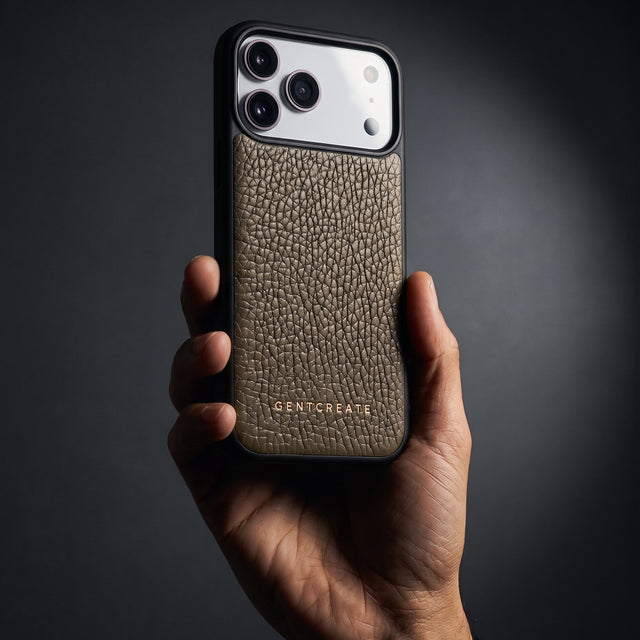 Hand holding a khaki pebble-grain leather iPhone 18 Pro Max case by GENTCREATE in a single studio light