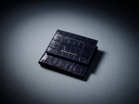 Tarjetero azul marino con grabado de cocodrilo sobre una cartera bifold a juego de GENTCREATE