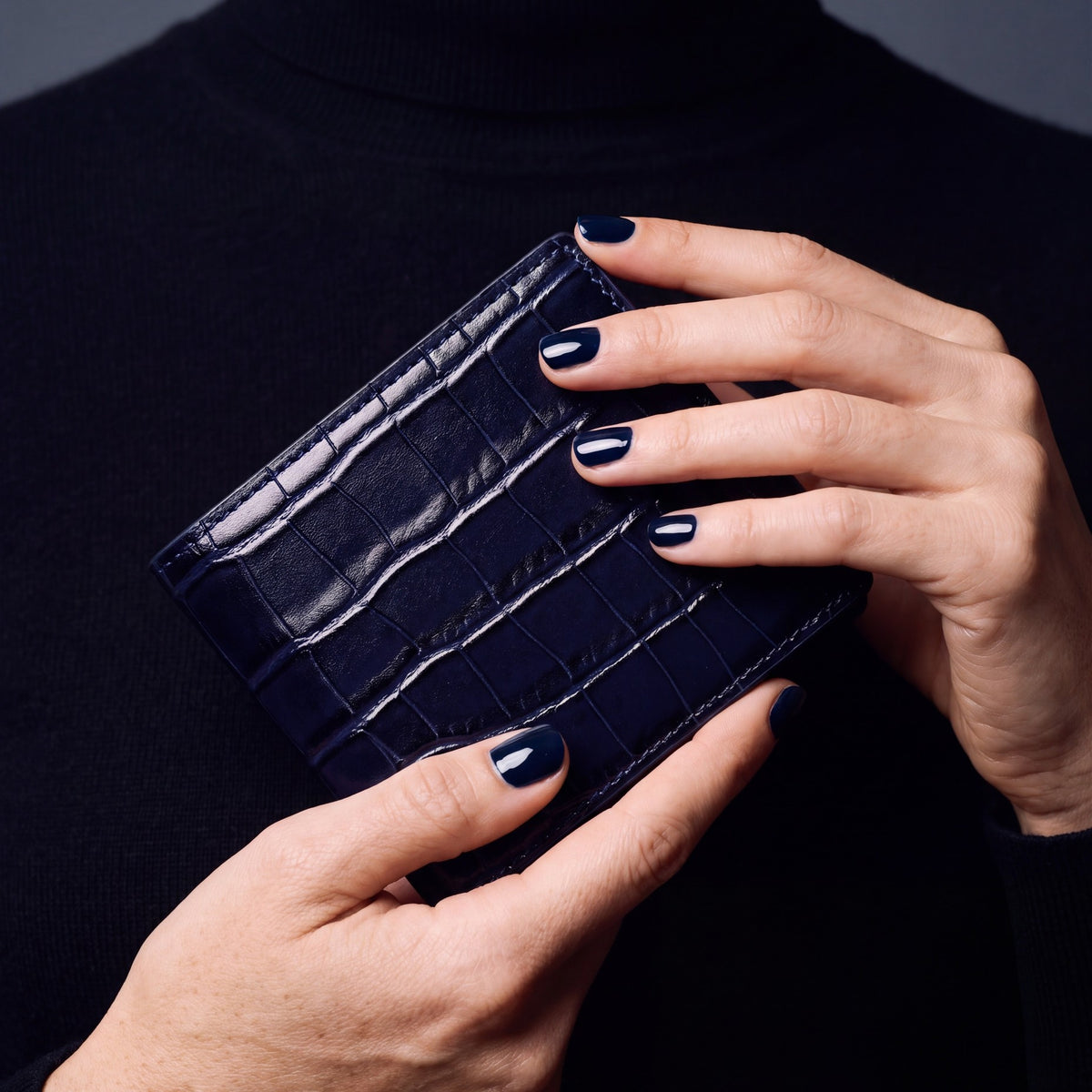 Close-up of hands holding a navy crocodile-embossed leather bifold wallet by GENTCREATE
