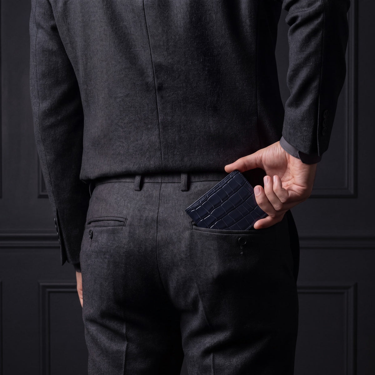 Man sliding a navy crocodile-embossed leather bifold wallet by GENTCREATE into his back trouser pocket