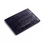 Navy crocodile-embossed leather card holder by GENTCREATE lying at an angle on white