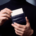 Close-up of hands holding a navy crocodile-embossed leather card holder by GENTCREATE with a card in the top slot