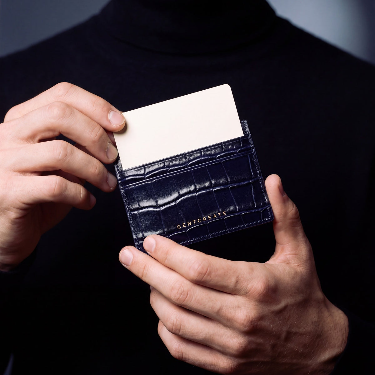 Close-up of hands holding a navy crocodile-embossed leather card holder by GENTCREATE with a card in the top slot