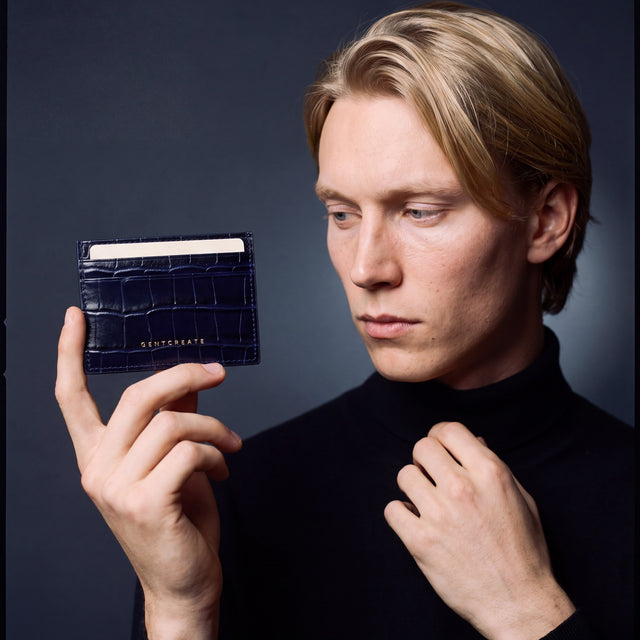 Man holding a slim navy crocodile-embossed leather card holder by GENTCREATE between two fingers