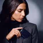 Woman slipping a navy crocodile-embossed leather card holder by GENTCREATE into a blazer chest pocket